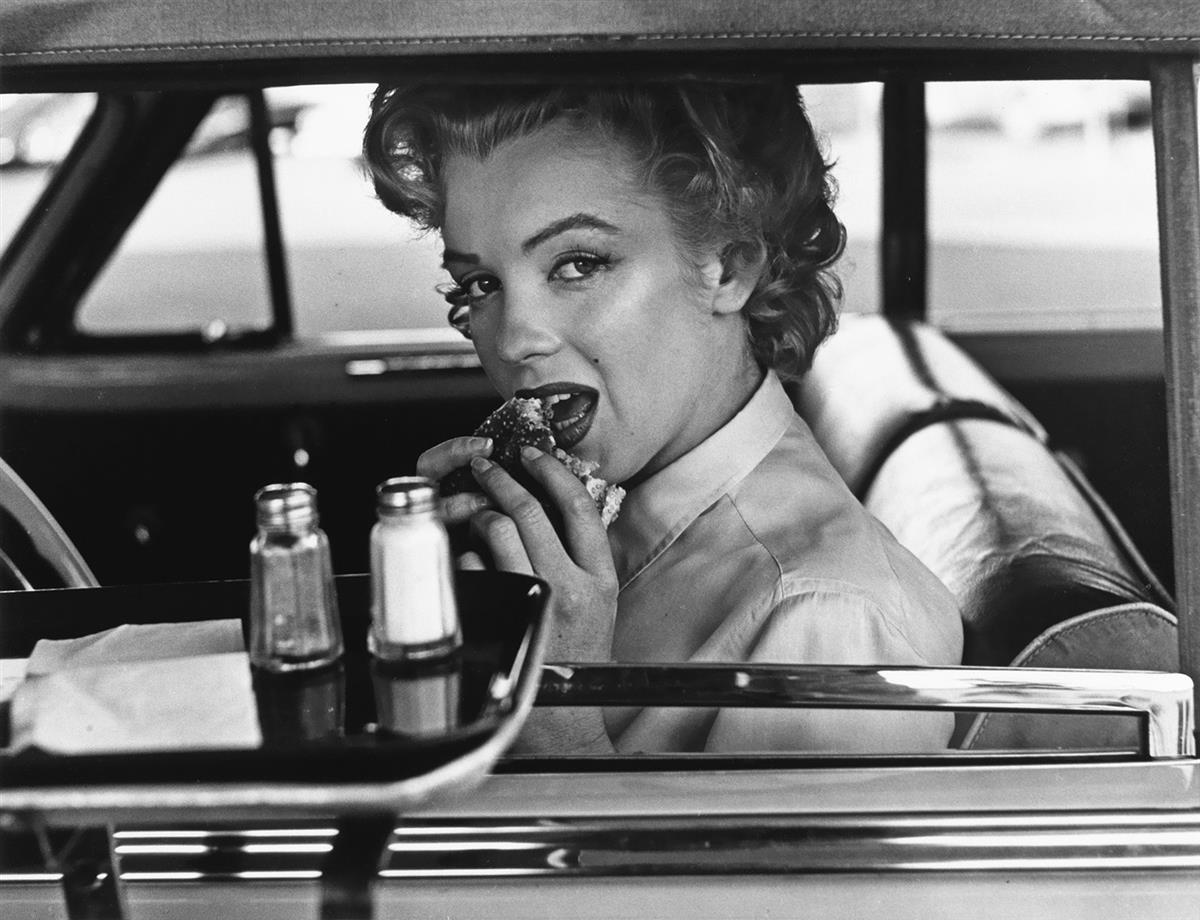 (PHILIPPE HALSMAN) (1906-1979)/STEPHEN GERSH (active 1980s) Marilyn Monroe eating a hamburger at a drive-in.
